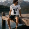 Man in Deer Mountain tee sitting on a lakeside dock - outdoor unisex tee Toronto