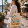 Woman carrying the Salt Sand & Sunshine canvas tote on a palm-lined promenade