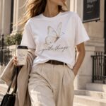 Woman wearing the Gentle Things butterfly t-shirt with a coffee on a city street - soft aesthetic tee - PrintMyVibe Toronto