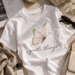 Gentle Things butterfly t-shirt styled flat with books and perfume - aesthetic white tee