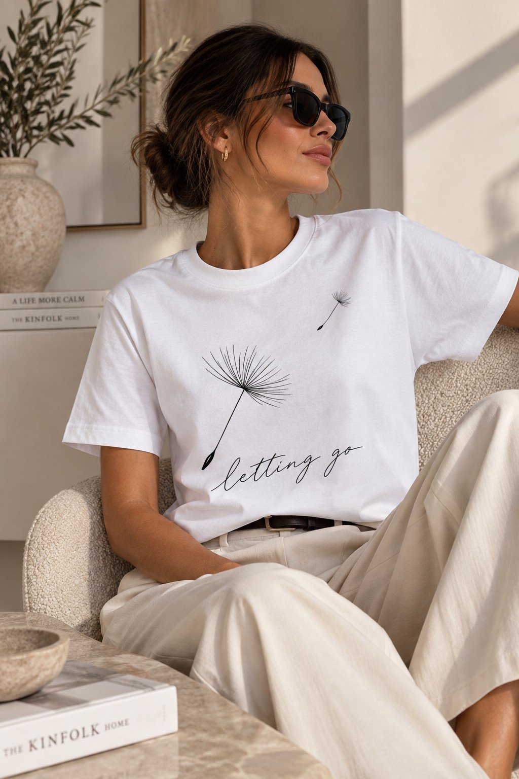 Letting Go dandelion t-shirt worn in an armchair - soft neutral aesthetic tee