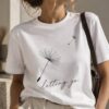 Woman wearing the Letting Go dandelion t-shirt with a shoulder bag - minimalist line art tee - PrintMyVibe Toronto